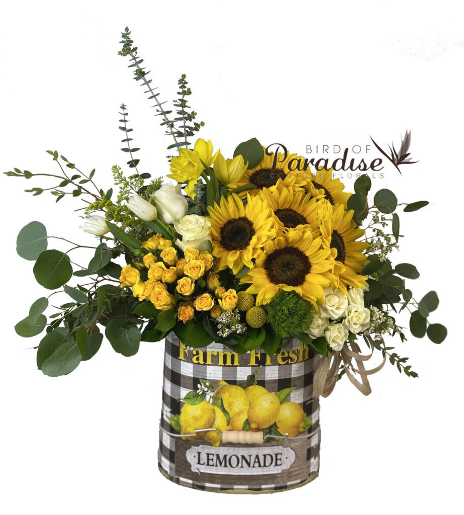 This rustic floral arrangement is a great way to celebrate the fall season. A rustic arrangement containing sunflowers, tulips, roses, spray roses, billy balls, and greenery in a tin container.
