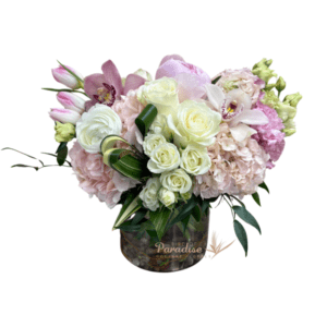 This soft pink flower arrangement includes roses, peony, tulips, hydrangea, spray roses, lisianthus, orchids, and greenery arranged in a cyllinder glass vase.